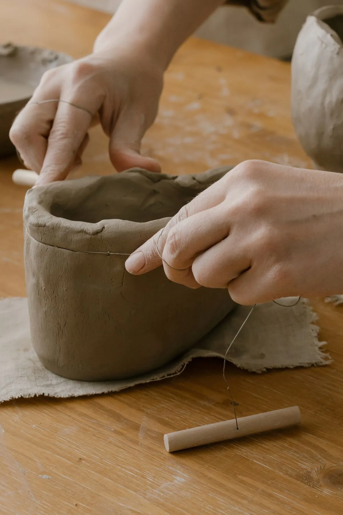 A maker shaping a clay pot by hand at a workbench; illustrative ceramics photograph